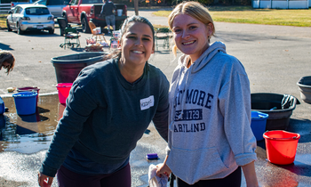 two women standing outside smiling while volunteering