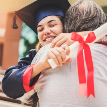 asian young female hugging her father with cap and gown on and diploma in hand