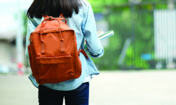 A person walks with an orange backpack