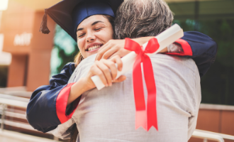young adult woman hugging her dad at college graduation