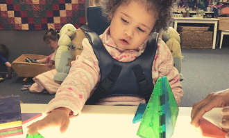 Young girl with disabilities using an adaptive toy in a classroom
