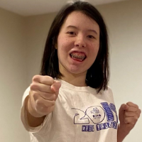 Naomi smiles and holds her fists up in a martial arts pose