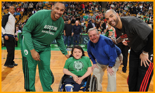 Sandy Ho sits on the center of the Celtics' court at TD Garden next to Celtics players and staff