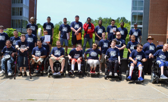 a group of youth leadership participants stands togtether in matching t-shirts for a group photo on a sunny day