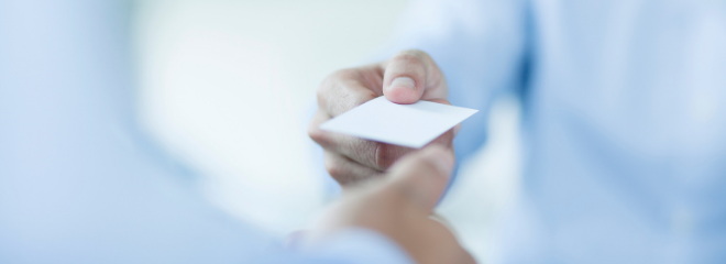 close up of one person is handing a small card to another person
