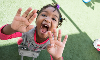a young girl smiles with her hands up