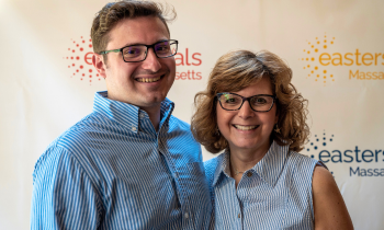 a man and woman smile in front of an ESMA step and repeat