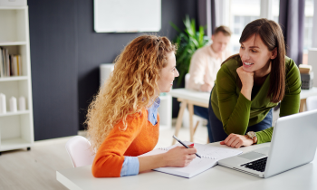 two women work at a computer together