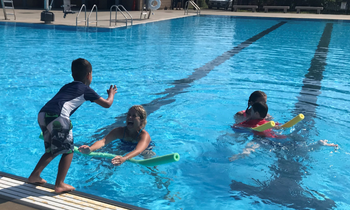 a child jumps into a lifeguards arms in the pool