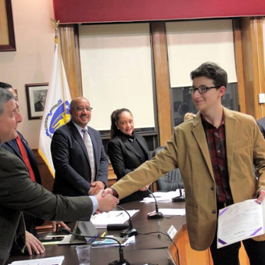 a young man shakes hands with an adult after a presentation