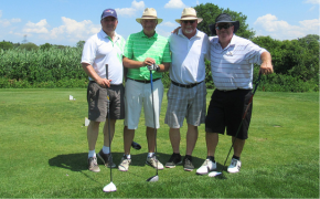 four men with golf clubs on a golf green on a sunny day