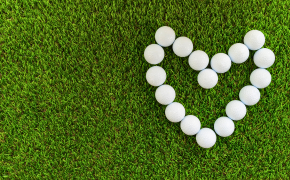 a heart made out of golf balls on green grass