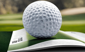 a golf ball sits on a printed program book sitting outside