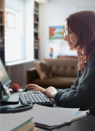 a woman sits at a desk using a computer inside her apartment