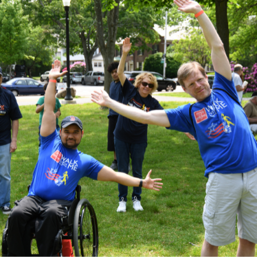 a man in a wheelchair and an older adult male doing stretches together in a park