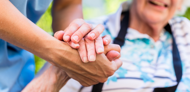 close up of adult holding elderly person's hand