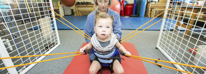 A young person with a physical disability receives rehabilitation services using equipment