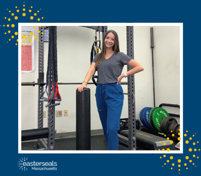 Kristina stands beside a large piece of physical therapy equipment and smiles