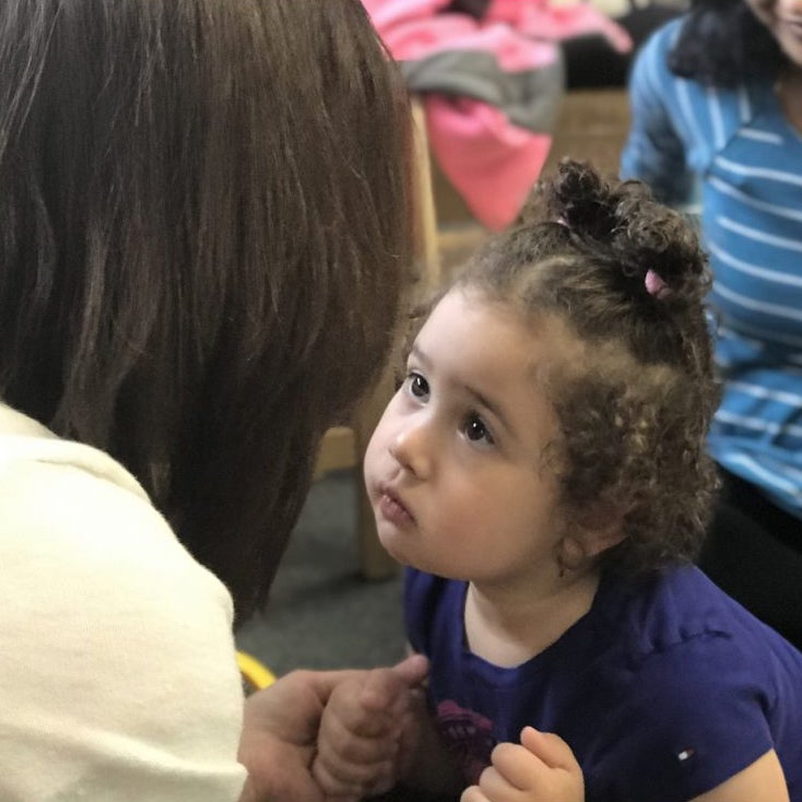 Close up of Rebecca looking at her teacher and holding her hands