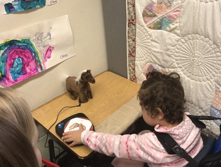 Rebecca sitting at a table playing with a switch toy