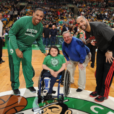 Sandy Ho sits on the center of the Celtics' court at TD Garden next to Celtics players and staff