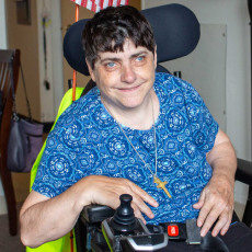 Sister Robin smiles while sitting in her wheelchair