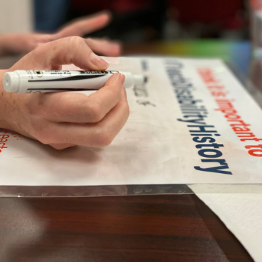 hand holding erasable marker writing a message on a sign
