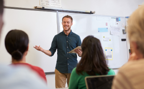 a teacher stands in front of his class in front of a white board