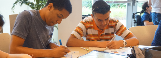 Two students sitting at a desk writing on papers.