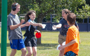 a group of kids and an employee play on a splashpad