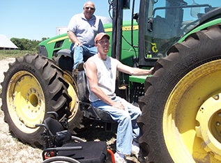 Young farmer man using lift to help him get up to the cabin of the tractor