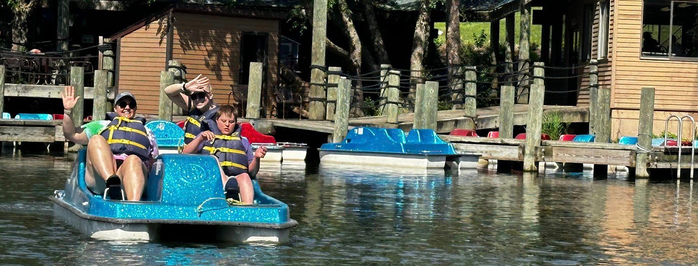 Camp family on paddle boat waving