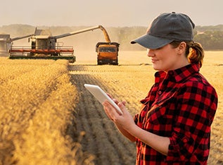 Woman farmer in field on tablet device