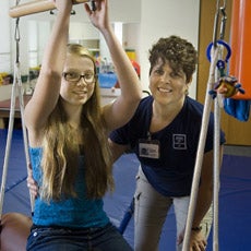 Teen working with therapist on equipment