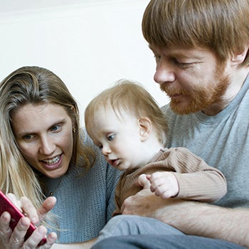 Parents with baby on lap playing with cell phone