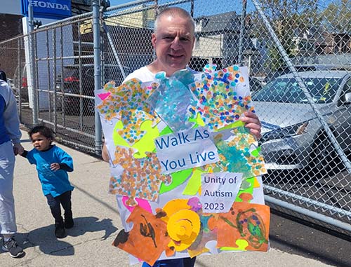 man holding sign in support of autism acceptance at ESNY walk for autism, April 2023