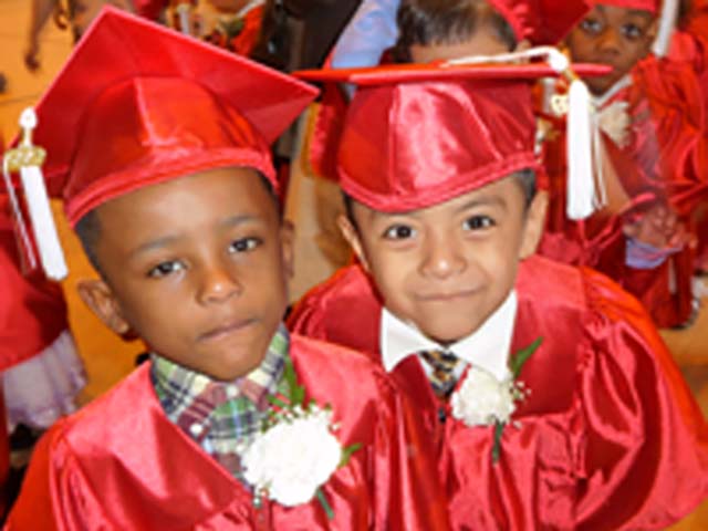 two small boys wearing red graduation caps and gowns