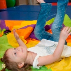 little girl lying on the floor looking up with her legs up in the air