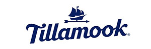 The word, "Tillamook", with a drawing of a ship above it with three sails. The ship sits on an arrow facing right. 
