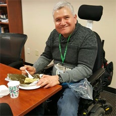 Jorge C, a Connecting Communities participant, smiling while eating in our classroom.