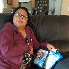 Connecting Communities participant, Leonor, relaxing on her couch at home.