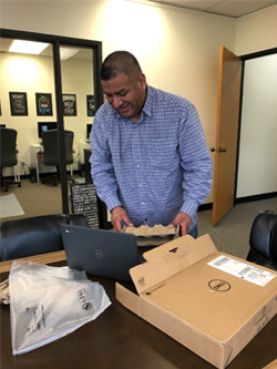 Latino man, happily receiving a laptop form the Connecting Communities program.