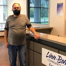 HVRP Participant, Orinn Savage, leaning on a counter in an office. He is wearing his safety mask.