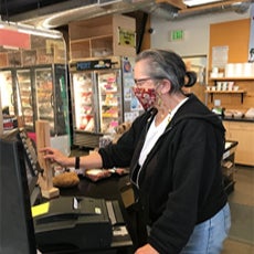 Senior woman, working as a cashier, wearing a protective mask.