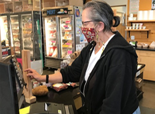 Senior woman, working as a cashier, wearing a protective mask.