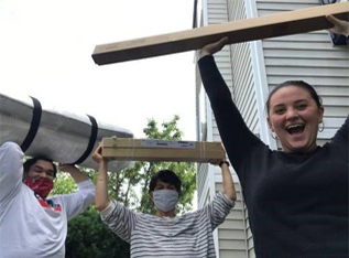 3 excited Supportive Services for Veteran Families program participants, carrying items as they move into their new home.