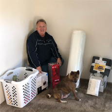 Supportive Services for Veteran Families program participant Mr. McGuire - posing with his dog and his welcome-home kit, in his new apartment.