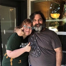 US Army Veteran, Robert and his wife, standing in front of their home. She is giving a 