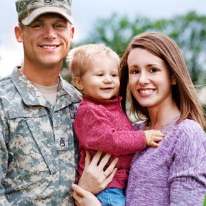 Smiling veteran (in uniform), with his family