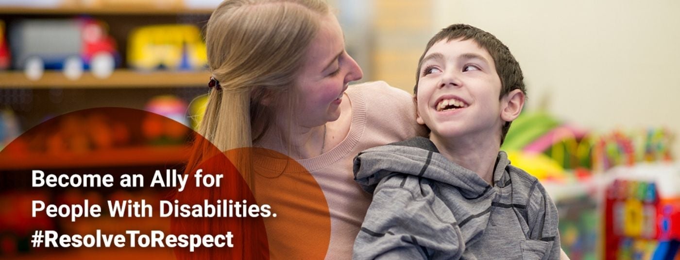 woman behind boy with her arms around him as they smile at eachother